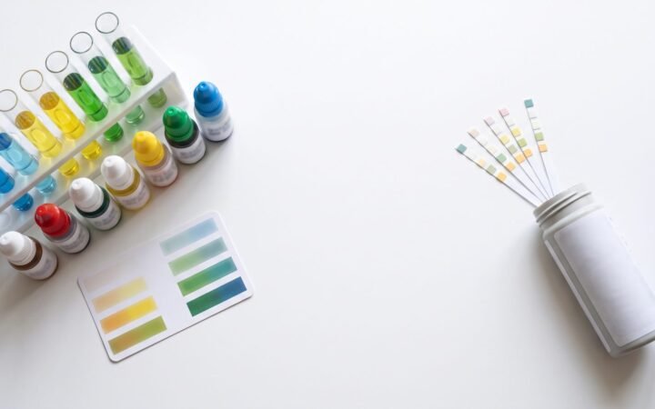 Liquid aquarium master test kit next to a bottle of paper test strips on a white table
